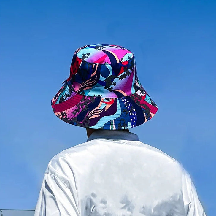Person wearing a colourful bucket hat against a clear blue sky